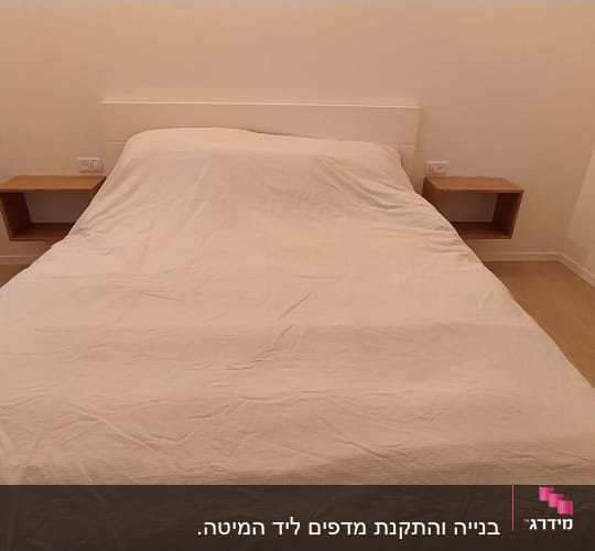מדף עץ מרחף ליד מיטה בחדר שינה